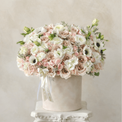 Large pastel rose arrangement in a round box on a pedestal