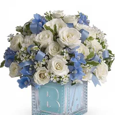 White roses and blue flowers in a glass block vase