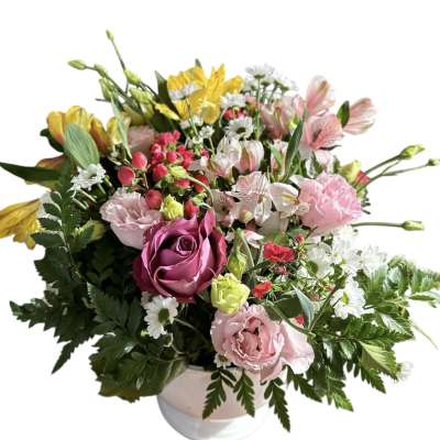 Mixed bouquet of pink, yellow, and white flowers in a white vase