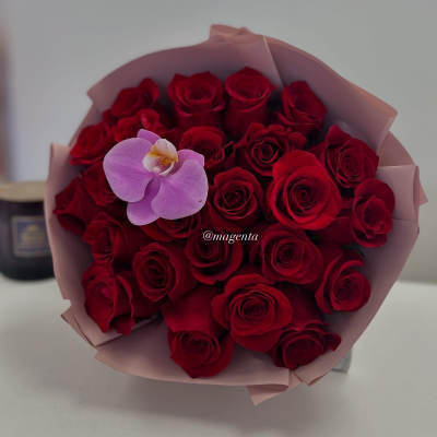 Bouquet of red roses with a single lavender orchid in pink wrap