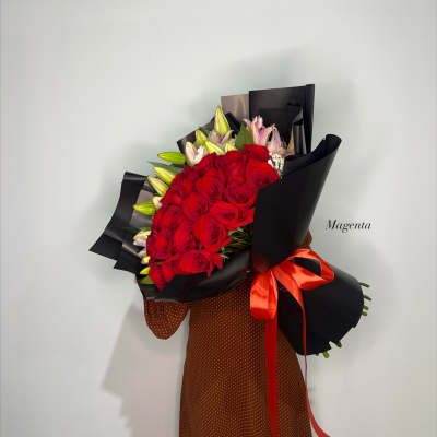 Bouquet of red roses and pink lilies wrapped in black paper