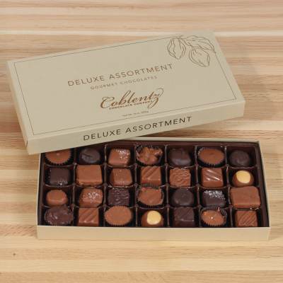 Open box of assorted chocolates on a wooden surface