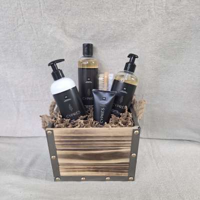 Wooden crate filled with black-labeled bath products and a small brush on shredded paper filler