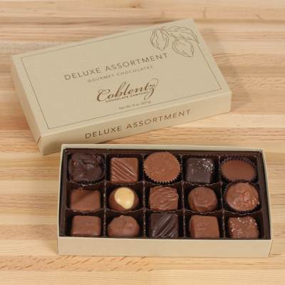Box of assorted chocolates with the lid beside it on a wooden surface