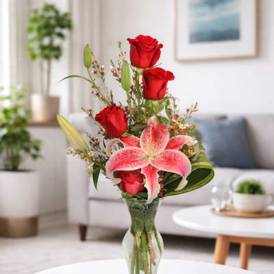 Red roses and pink lilies arranged in a clear glass vase