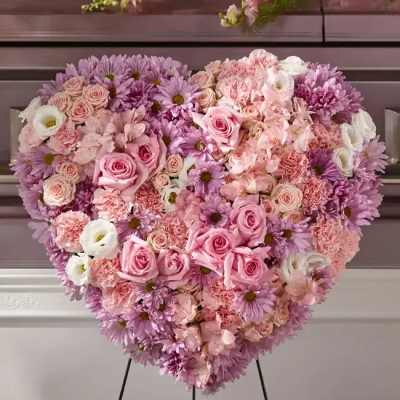 Heart-shaped floral arrangement of pink and lavender flowers on a stand