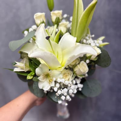 White lily and rose bouquet with baby's breath in a clear vase