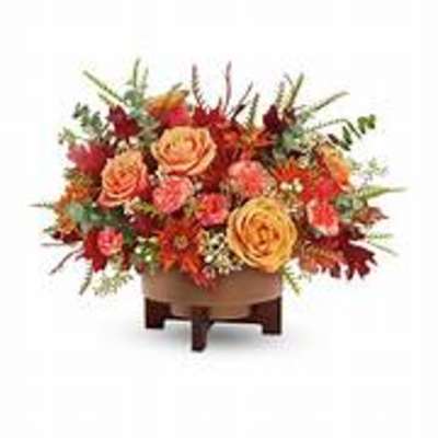 Orange and red floral arrangement in a low wooden container