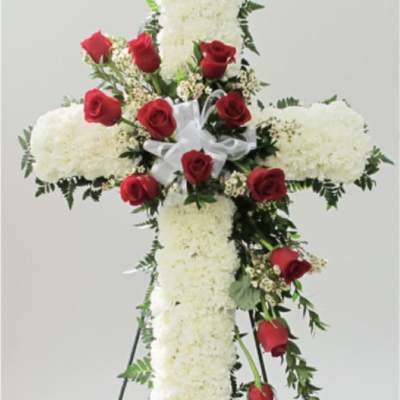 White floral cross with red roses on a stand