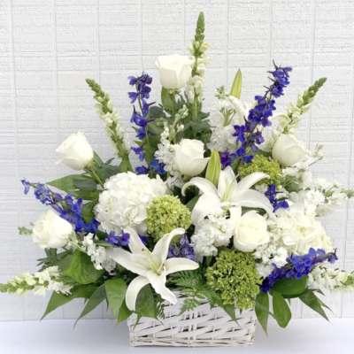 White lilies and roses with blue flowers in a white basket