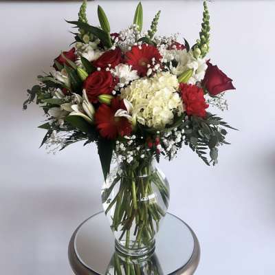 Red and white mixed flower bouquet in a clear glass vase