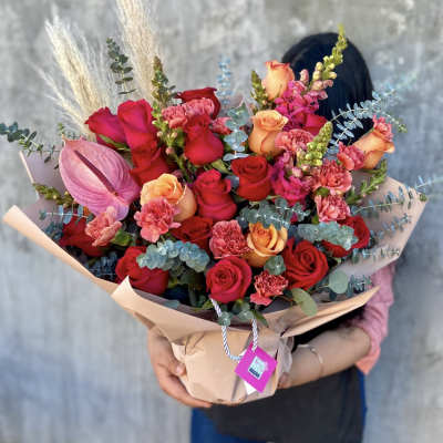 Bouquet of red and peach roses with pink carnations and an anthurium