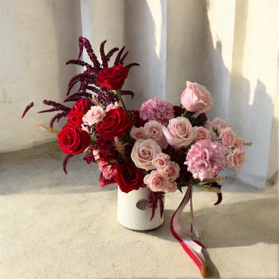 Bouquet of red and blush roses in a white vase