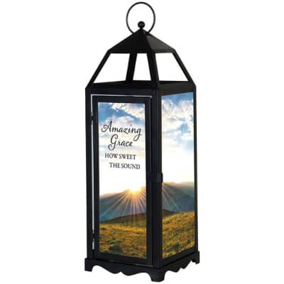 Tall black lantern with glass panels showing a sunrise landscape and the words "Amazing Grace, How Sweet the Sound."