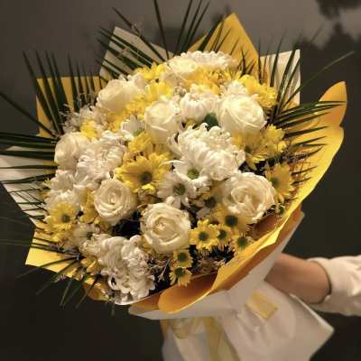 Bouquet of white and yellow flowers wrapped in white and yellow paper