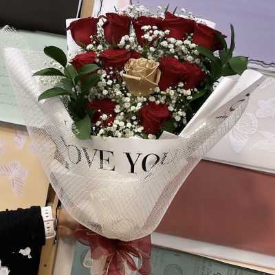 Bouquet of red and gold roses wrapped in white mesh with a ribbon
