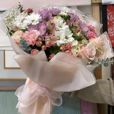 Bouquet of pink and white flowers wrapped in pale pink paper