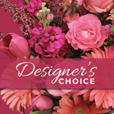 Pink floral arrangement with roses, tulips, and daisies behind a Designer's Choice banner