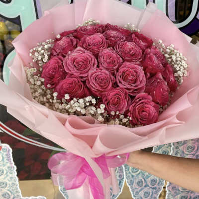 Pink rose bouquet wrapped in pale pink paper with baby's breath