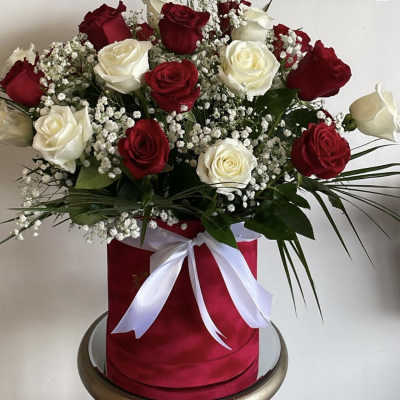 Red and white roses arranged in a red hat box with a white ribbon