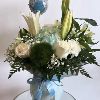 Bouquet of white lilies, roses, and blue hydrangea with a baby boy balloon