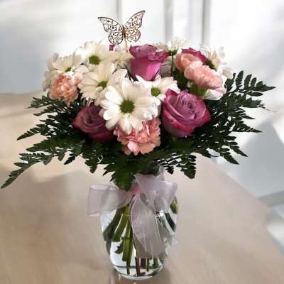 Pink roses and white daisies in a glass vase with a ribbon