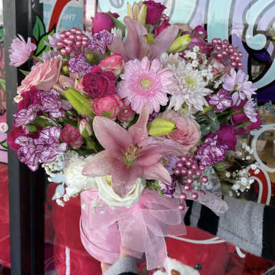 Pink mixed bouquet with lilies, roses, and daisies in a pink hatbox