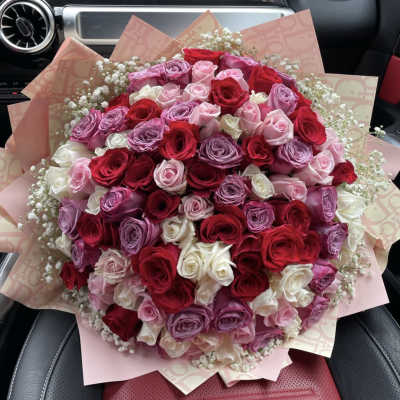 Large bouquet of red, pink, and white roses wrapped in pink paper