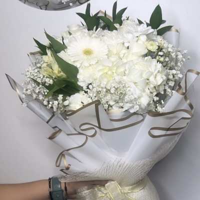 White bouquet with gerbera daisies, hydrangeas, and baby's breath wrapped in white paper