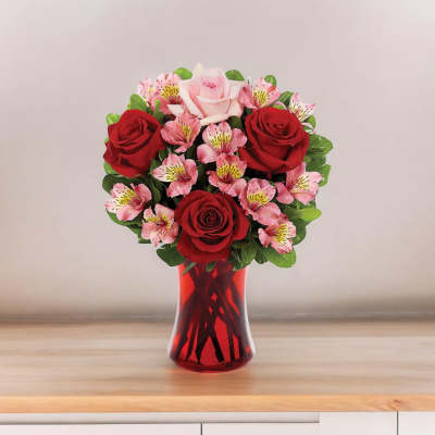 Bouquet of red and pink roses in a red glass vase
