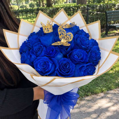 Bouquet of blue roses wrapped in white paper with gold trim