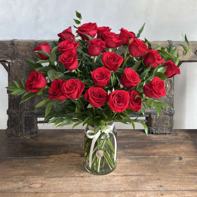 Bouquet of red roses in a clear glass vase with a white ribbon