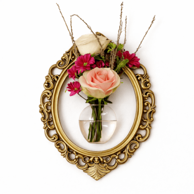 Small floral arrangement in a clear wall vase inside an ornate gold frame