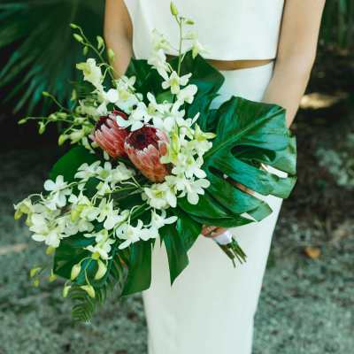Bride holding a bouquet of white orchids and pink protea