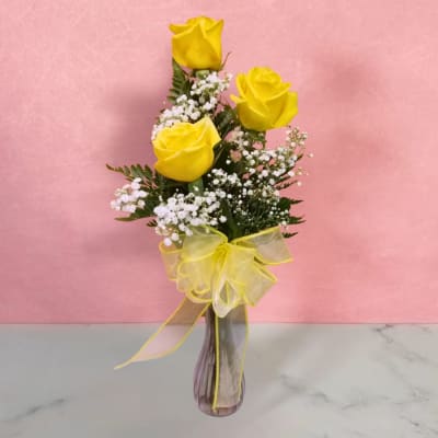 Yellow roses in a glass vase with a yellow ribbon bow
