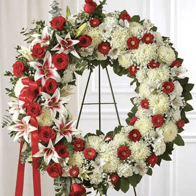 Heart-shaped floral wreath with red roses and white flowers on a stand