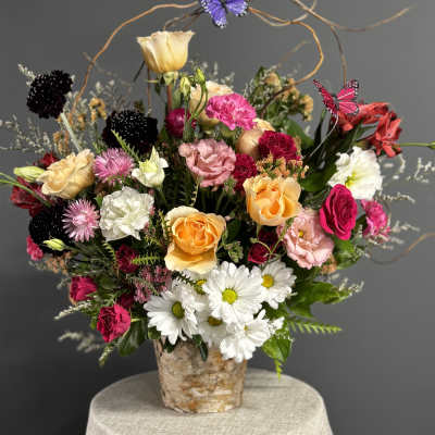 Mixed bouquet of roses, daisies, and carnations in a birch-style container