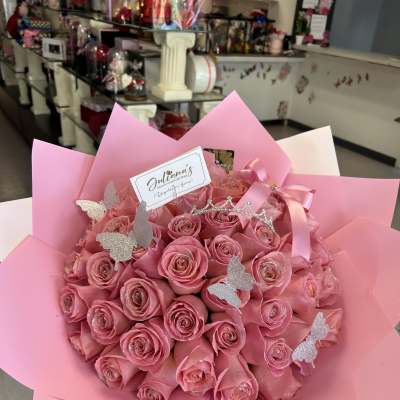 Bouquet of pink roses wrapped in pink paper with butterfly picks