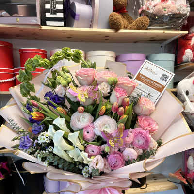 Large pastel bouquet with pink, purple, and white flowers wrapped in blush paper