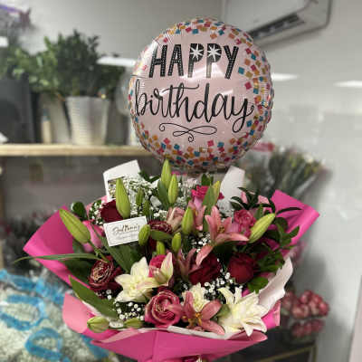 Pink birthday balloon above a bouquet of lilies and roses