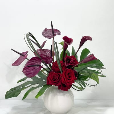 Red roses and burgundy calla lilies in a white vase