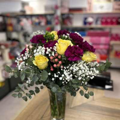 Bouquet of yellow and purple roses in a clear glass vase