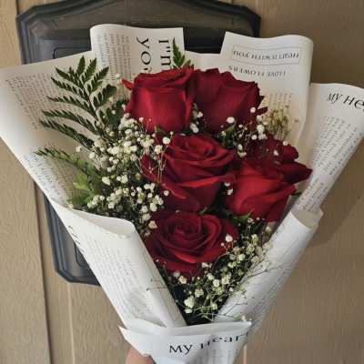 Bouquet of red roses with baby's breath in printed white wrap