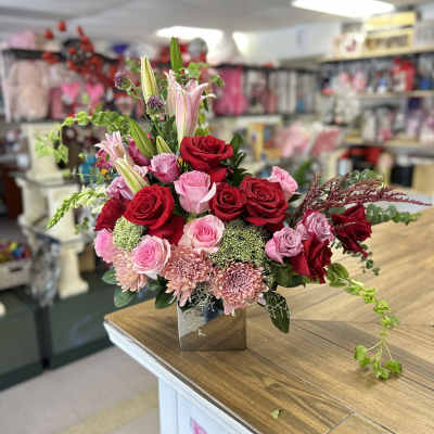 Bouquet of red and pink roses with lilies in a square vase