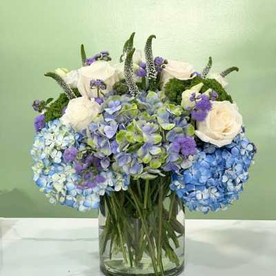 Blue hydrangeas and white roses arranged in a glass vase