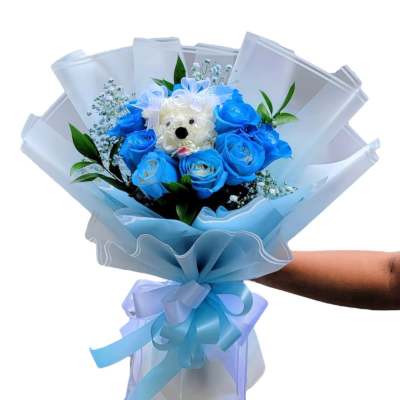 Blue rose bouquet with a small teddy bear center and ribbon wrap