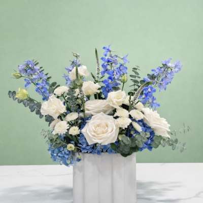 Blue and white floral arrangement in a white container