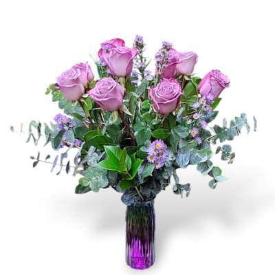 Lavender roses in a purple glass vase with small purple filler flowers