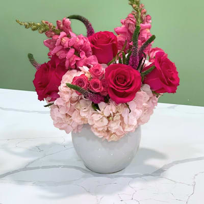 Pink roses and hydrangeas arranged in a white vase