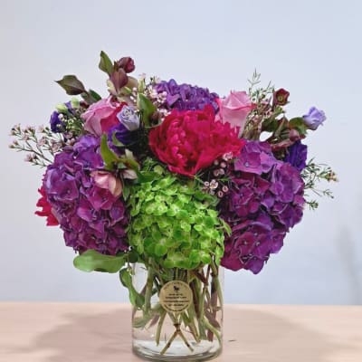 Colorful bouquet of purple, pink, and green flowers in a clear glass vase